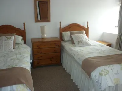 a bedroom with two beds and a dresser at HOPSLAND HOLIDAYS Byre, Dairy & Hayloft in Saint Cleer
