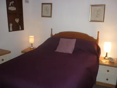a bedroom with a bed with a purple blanket and two lamps at HOPSLAND HOLIDAYS Byre, Dairy & Hayloft in Saint Cleer