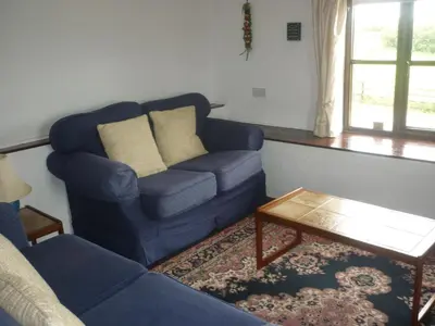 a living room with a blue couch and a coffee table at HOPSLAND HOLIDAYS Byre, Dairy & Hayloft in Saint Cleer