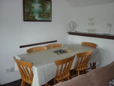 a dining room table with chairs and a table and a picture at HOPSLAND HOLIDAYS Byre, Dairy & Hayloft in Saint Cleer