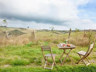 a wooden table and two chairs sitting in a field at Byre in Saint Martin