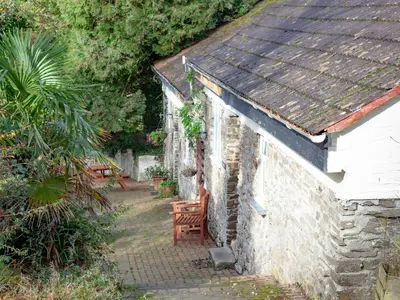 a small stone building with a bench next to it at Smithy in Saint Martin