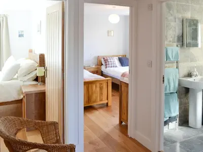 a bedroom with a bed and a bathroom with a sink at Little Owl Lodge in Saint Columb Major