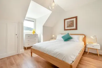 a white bedroom with a bed and a window at 1 Bed in Looe oc-s29019 in Looe