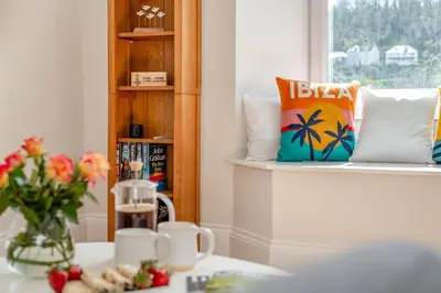 a room with a table with a vase of flowers and a window at 1 Bed in Looe oc-s29019 in Looe