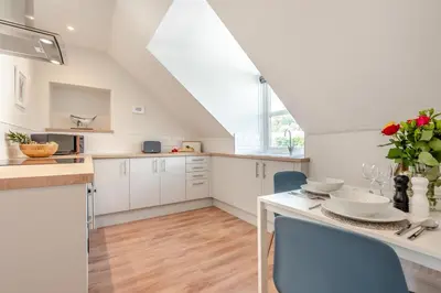 a kitchen with white cabinets and blue chairs at 1 Bed in Looe oc-s29019 in Looe