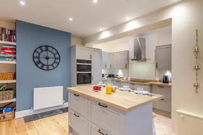a kitchen with white cabinets and a clock on the wall at 3 Bed in Looe oc-s29266 in Looe