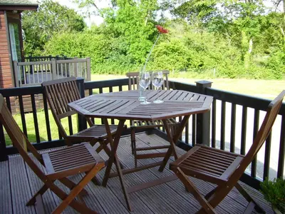 a wooden table and two chairs on a deck at Rosewater Park Lodge in Bodmin