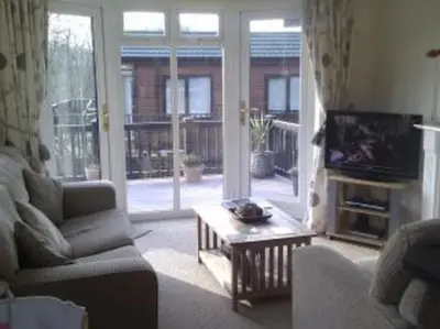 a living room with a couch and a tv and a table at Rosewater Park Lodge in Bodmin