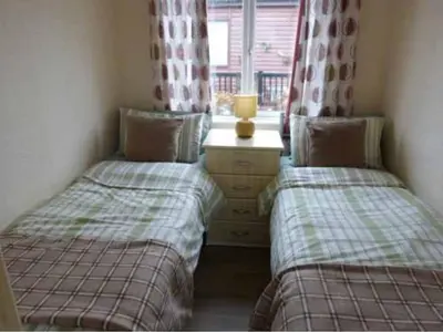 two twin beds in a small room with a window at Rosewater Park Lodge in Bodmin