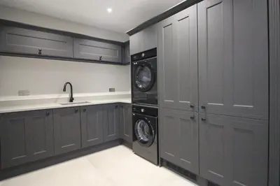 a kitchen with gray cabinets and a washer and dryer at Luxury holiday home with HOT TUB in St Merryn