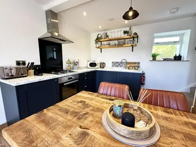 a kitchen with a wooden table and blue cabinets at The Little Cottage at Porth in Newquay