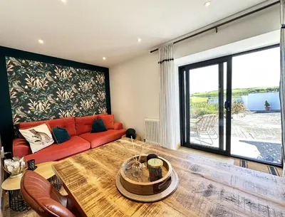a living room with a red couch and a table at The Little Cottage at Porth in Newquay