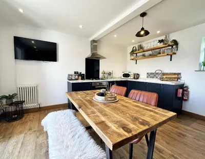 a kitchen and dining room with a wooden table at The Little Cottage at Porth in Newquay