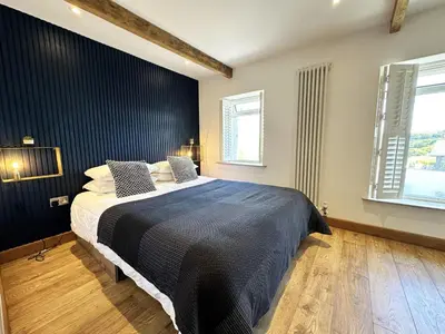 a bedroom with a bed and two windows at The Little Cottage at Porth in Newquay