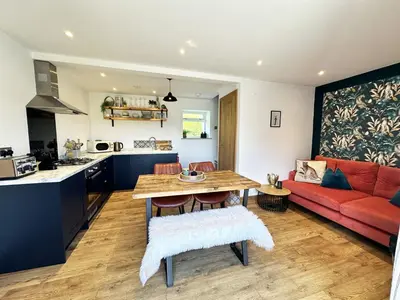 a kitchen and living room with a red couch at The Little Cottage at Porth in Newquay