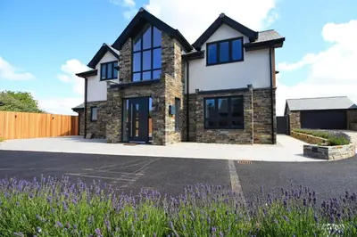 a house with a driveway and purple flowers at Stylish home with HOT TUB in St Merryn