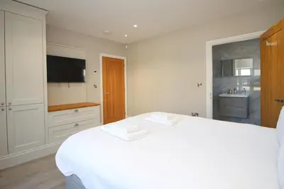 a bedroom with a white bed and a television at Stylish home with HOT TUB in St Merryn