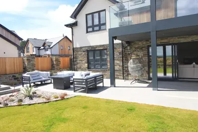 a house with a patio and a lawn at Stylish home with HOT TUB in St Merryn