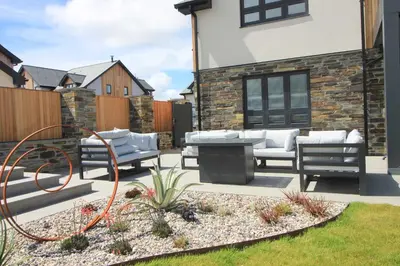 a patio with chairs and a tv in a yard at Stylish home with HOT TUB in St Merryn