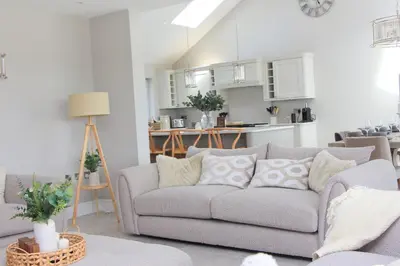 a living room with a gray couch and a kitchen at Stylish home with HOT TUB in St Merryn