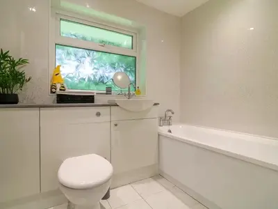 a bathroom with a toilet and a sink and a window at Beekeepers Cottage in Liskeard