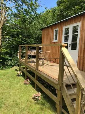 a large wooden deck next to a tiny house at Shepherd's hut at Rosewood House in Liskeard