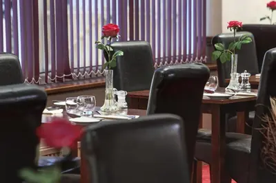 a table with a vase with a rose in it at Best Western Fowey Valley in Lostwithiel