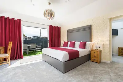 a bedroom with a large bed with red curtains at Best Western Fowey Valley in Lostwithiel
