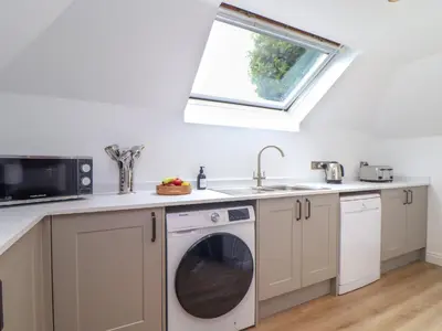 a kitchen with a washing machine and a window at Squirrels Leap in Falmouth