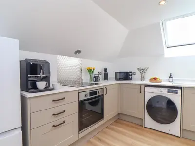 a kitchen with white cabinets and a washer and dryer at Squirrels Leap in Falmouth