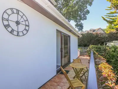 a clock on the side of a house with two chairs at Lake View in Falmouth