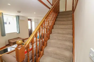 a winding staircase in a home with wooden railings at Ebrenn in Tintagel