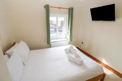 a bedroom with a bed with white sheets and a window at Ebrenn in Tintagel