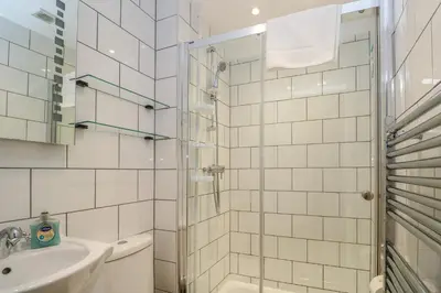 a white bathroom with a shower and a sink at Ebrenn in Tintagel