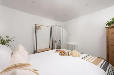a bedroom with a white bed with a mirror at Mount Pleasant, St Ives in St Ives