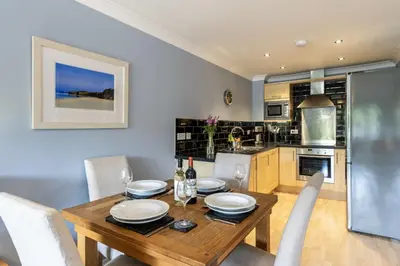 a kitchen and dining room with a wooden table and chairs at 3 Waves in Newquay