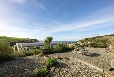 a patio with a table and a bench and the ocean at 3 Waves in Newquay