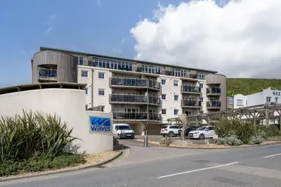 an apartment building with cars parked in a parking lot at 3 Waves in Newquay