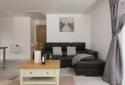 a living room with a black couch and a table at The Wood Shed in Perranporth