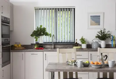 a kitchen with white cabinets and a table with fruit at The Wood Shed in Perranporth