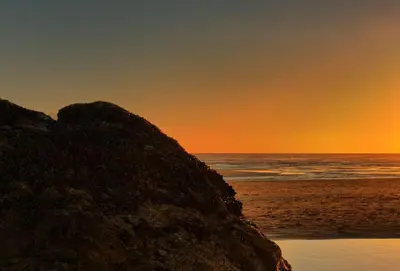 a sunset on the beach with a large rock at The Wood Shed in Perranporth