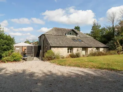 an old stone house with a gravel driveway at Stable Loft in Newquay