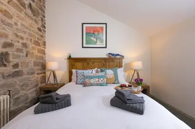 a bedroom with a large white bed with two lamps at Stable Loft in Newquay