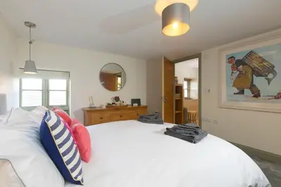 a bedroom with a white bed and a mirror at Stable Loft in Newquay