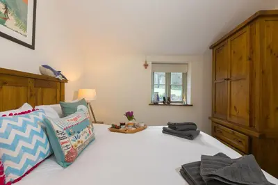 a bedroom with a white bed with a wooden cabinet at Stable Loft in Newquay