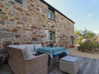 a patio with a table and chairs and a brick building at Stable Loft in Newquay
