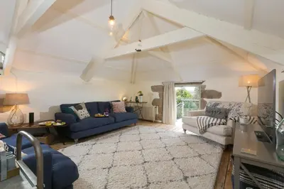 a living room with two blue couches and a rug at Stable Loft in Newquay