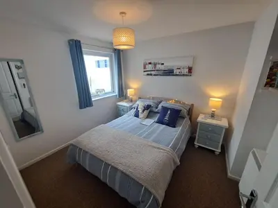 a bedroom with a bed with blue pillows and a window at Willow Bungalow Quiet and secluded in Carbis Bay