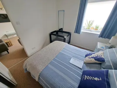 a bedroom with a bed with a blue blanket and a window at Willow Bungalow Quiet and secluded in Carbis Bay